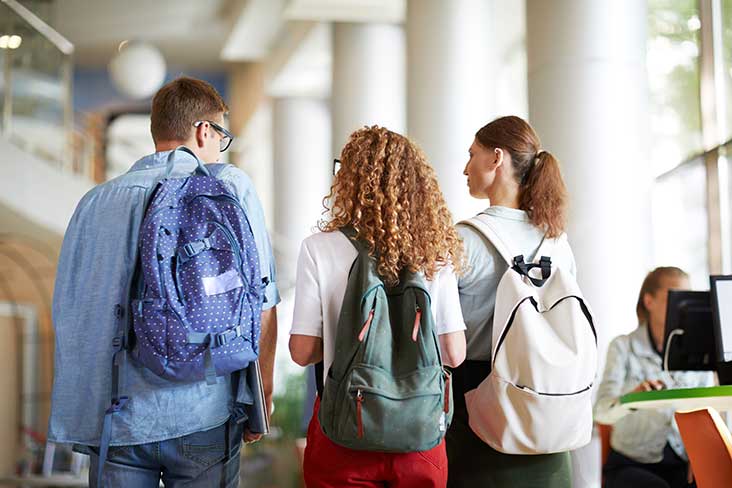 three students with backpacks walking to class